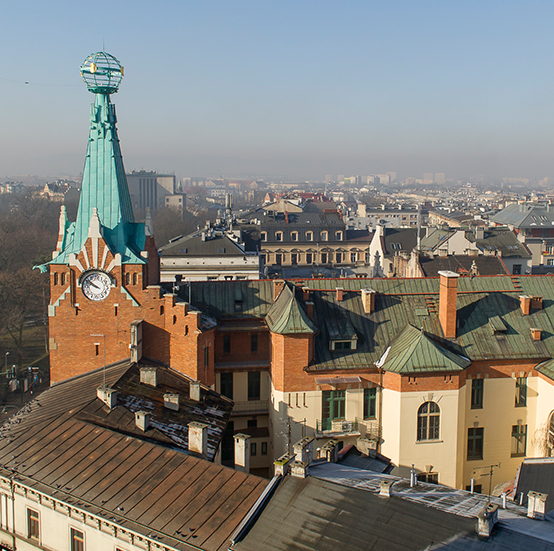 Widok z lotu ptaka na wieżę kamienicy Pod Globusem ze zwieńczającą ją sferą armilarną, na tle dachów Krakowa.